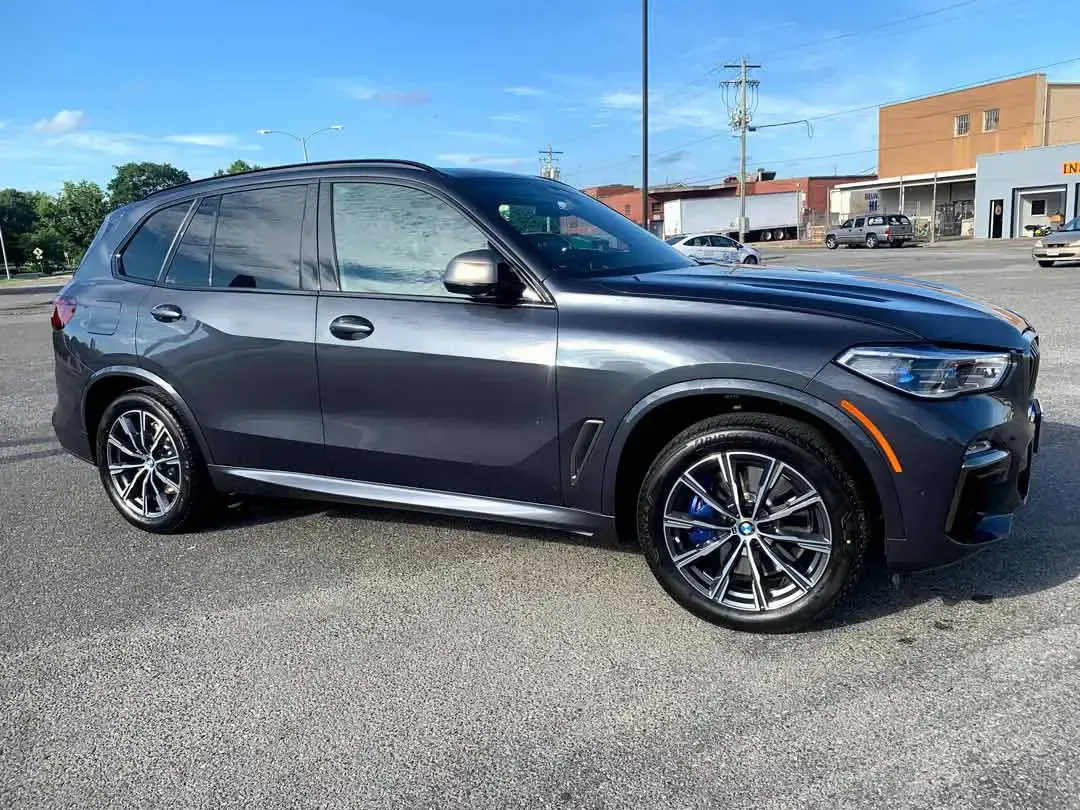 A gray bmw x5 is parked in a parking lot.