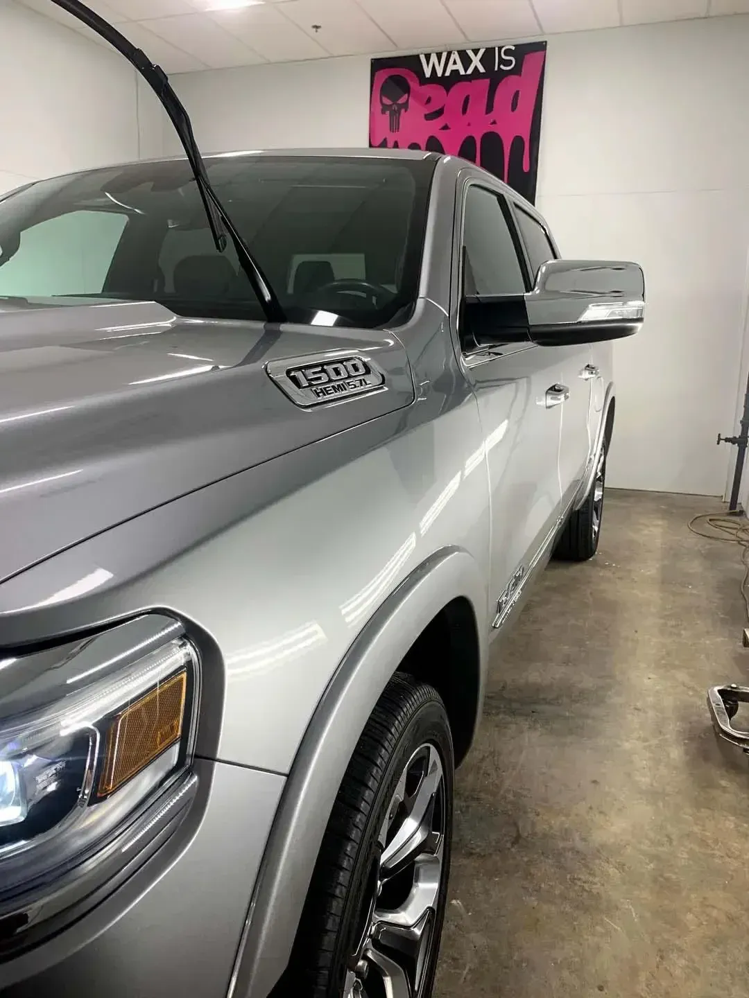 A silver truck is parked in a garage next to a sign that says wax is.