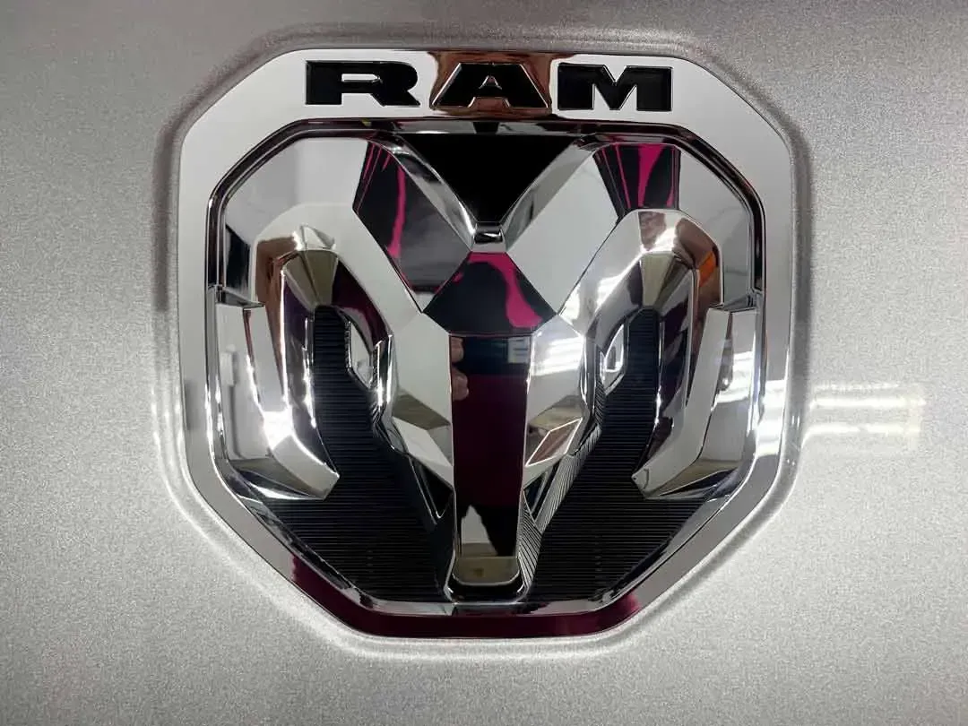 A close up of a ram logo on a silver car