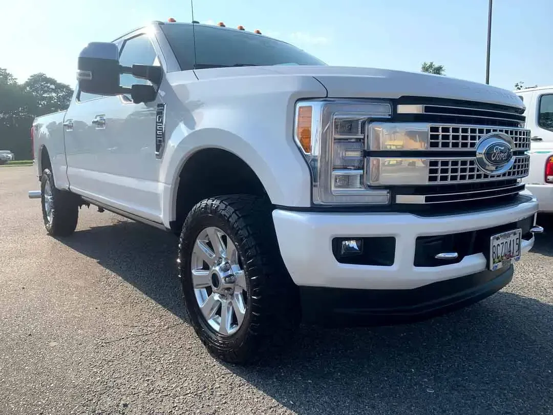 A white ford truck is parked in a parking lot.