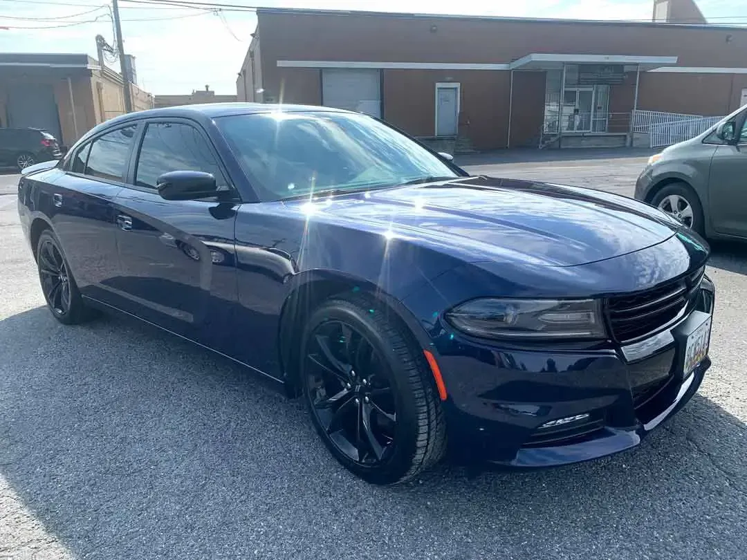A blue dodge charger is parked in a parking lot in front of a building.