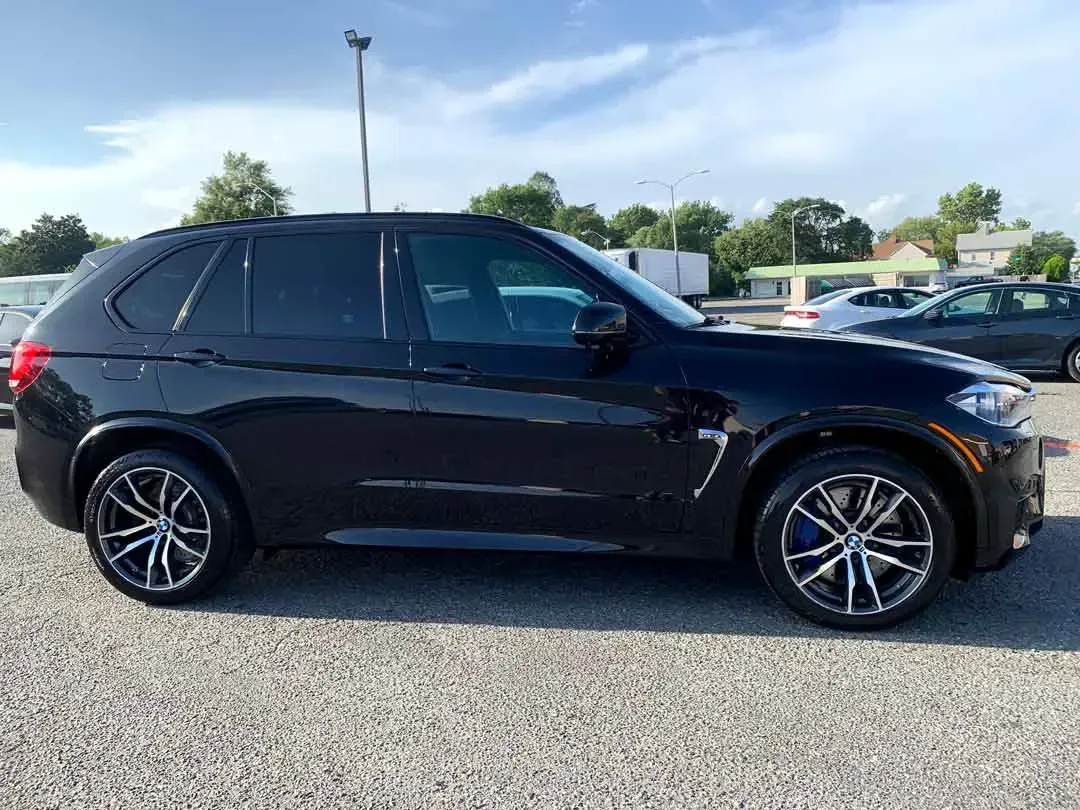 A black bmw x5 is parked in a gravel lot.