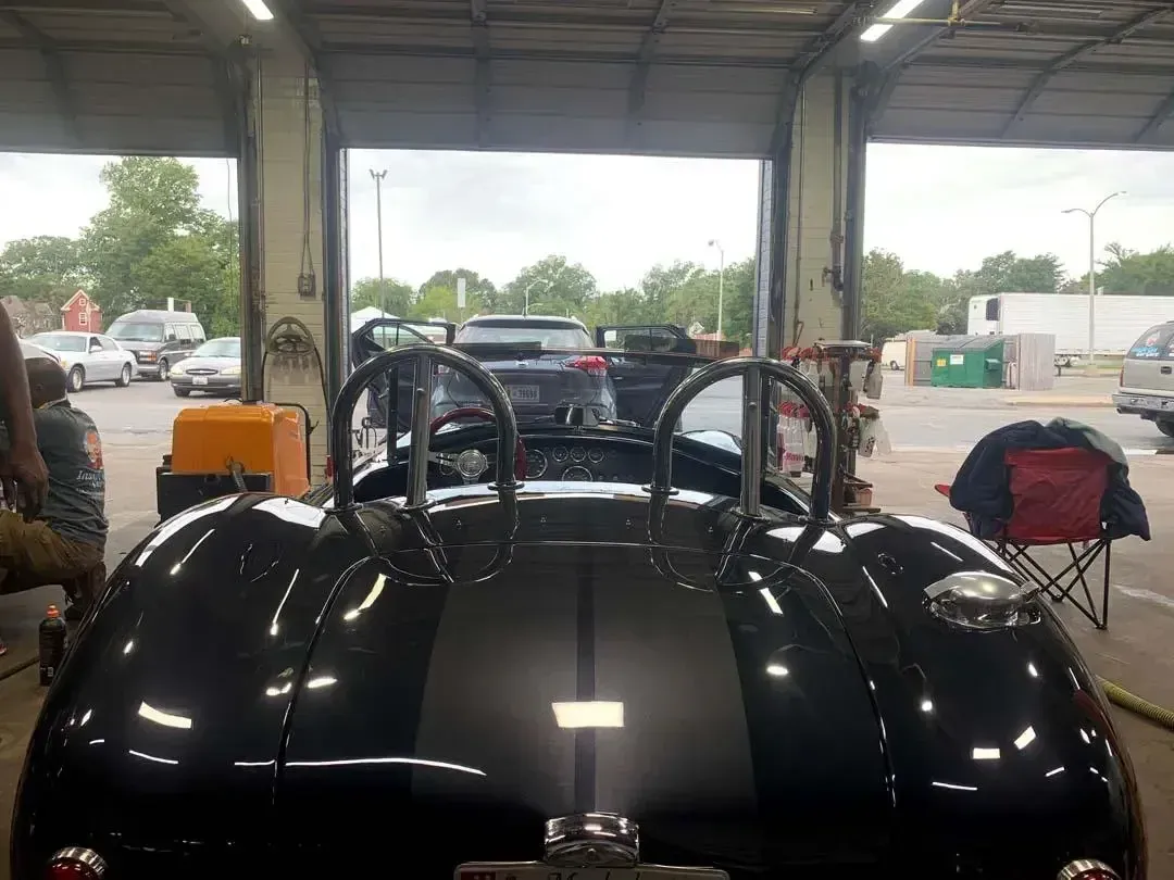 A black sports car is parked in a garage.
