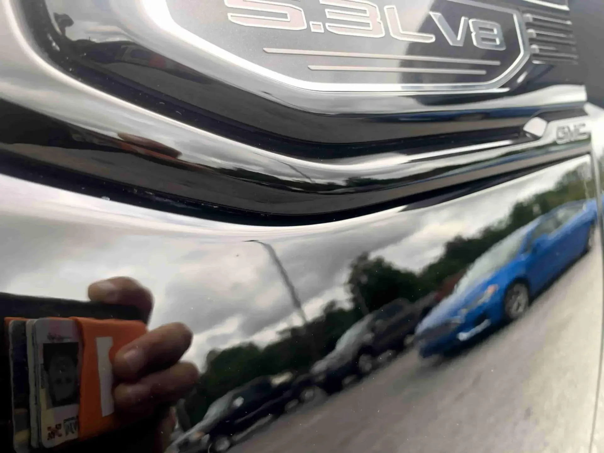 A person is taking a picture of the front of a dodge ram truck.
