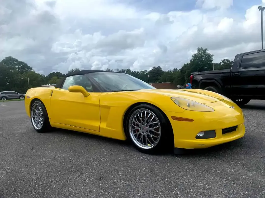 A yellow corvette convertible is parked in a parking lot.