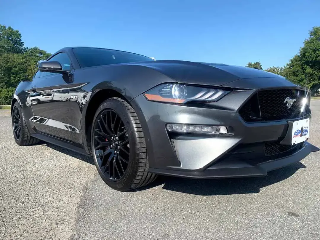 A gray ford mustang is parked in a parking lot.