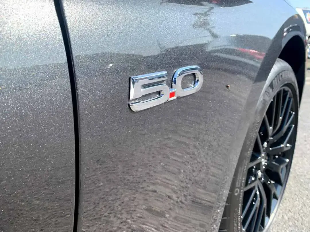 A close up of a ford mustang 5.0 emblem on the side of a car.