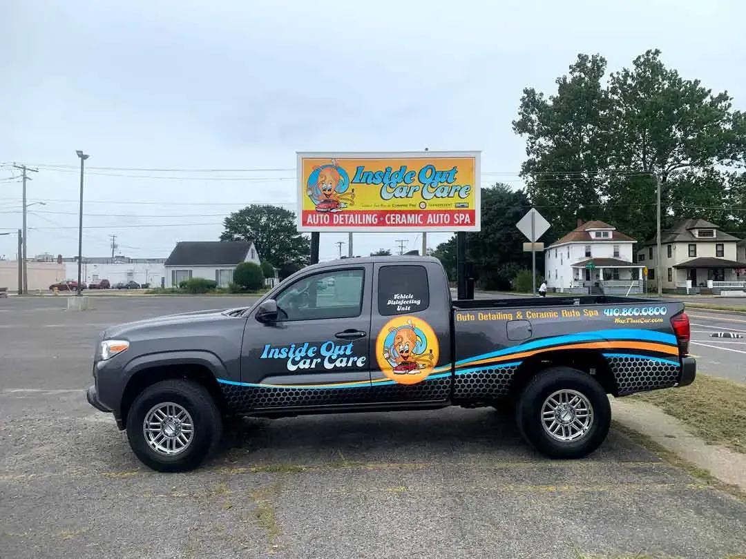 A truck is parked in a parking lot next to a billboard.