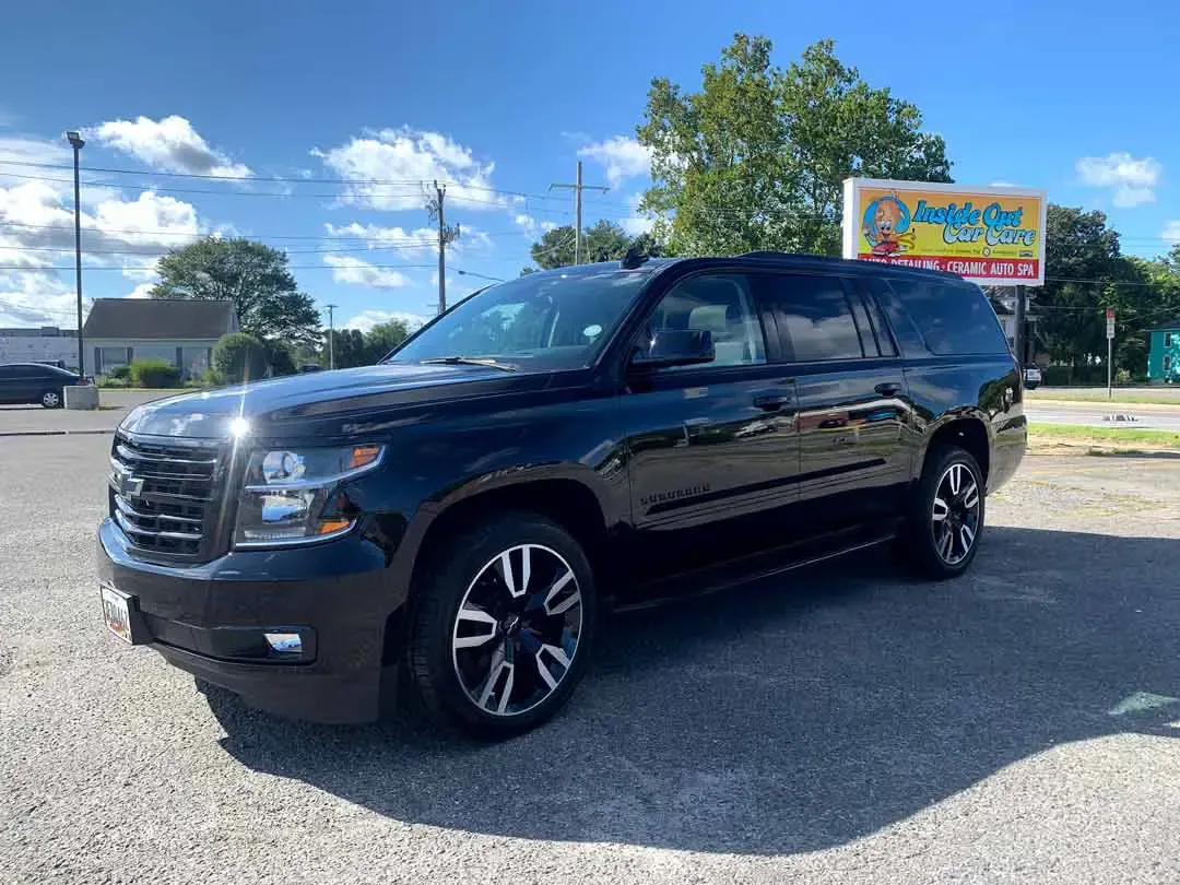 A black suv is parked in front of a car dealership.