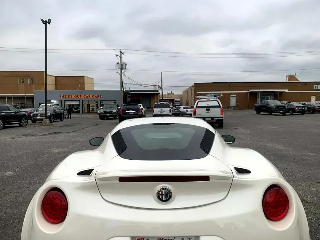 A white sports car is parked in a parking lot in front of a building.