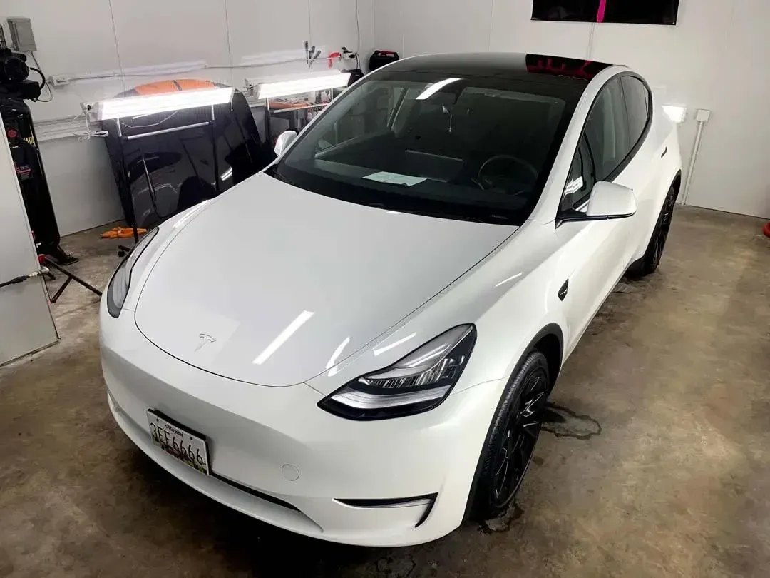 A white tesla model y is parked in a garage.