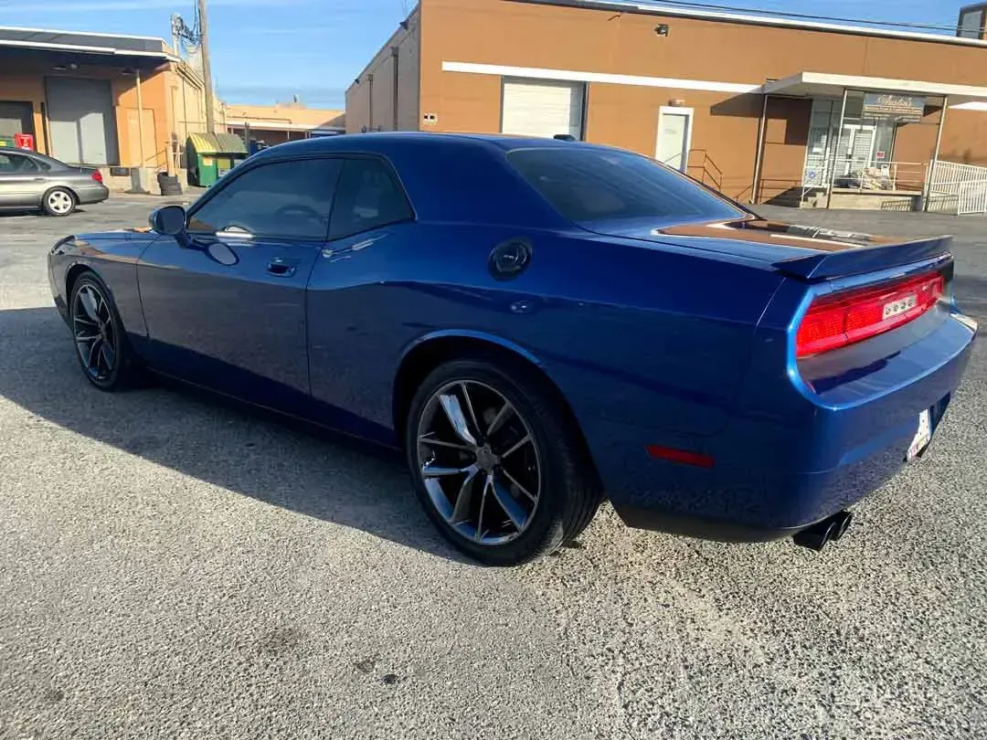 A blue dodge challenger is parked in front of a building.