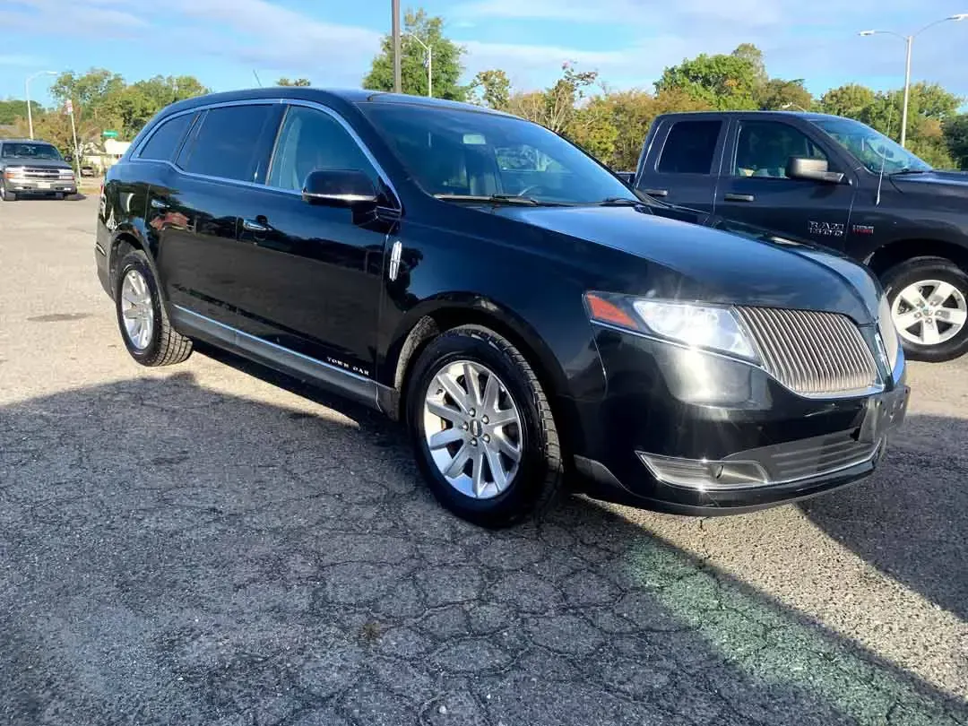 A black lincoln mkx is parked in a parking lot next to a truck.