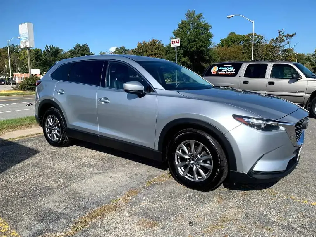 A silver mazda cx 9 is parked in a parking lot.