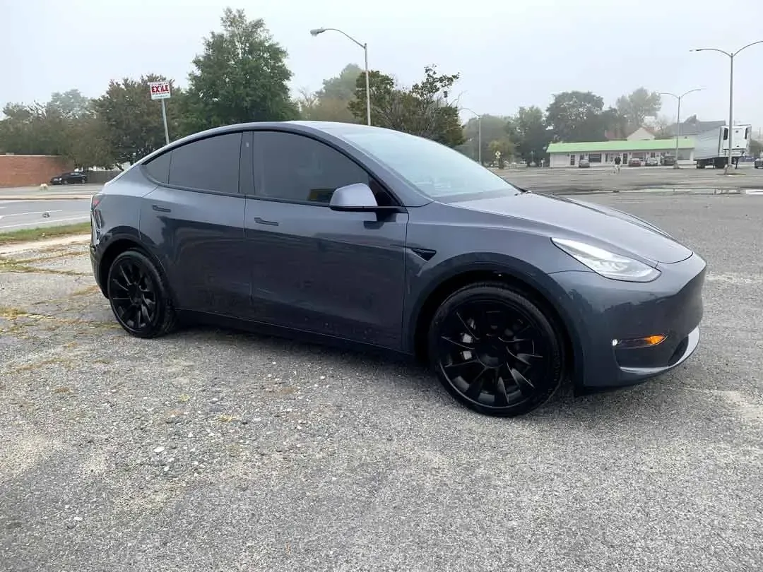 A tesla model y is parked in a parking lot.
