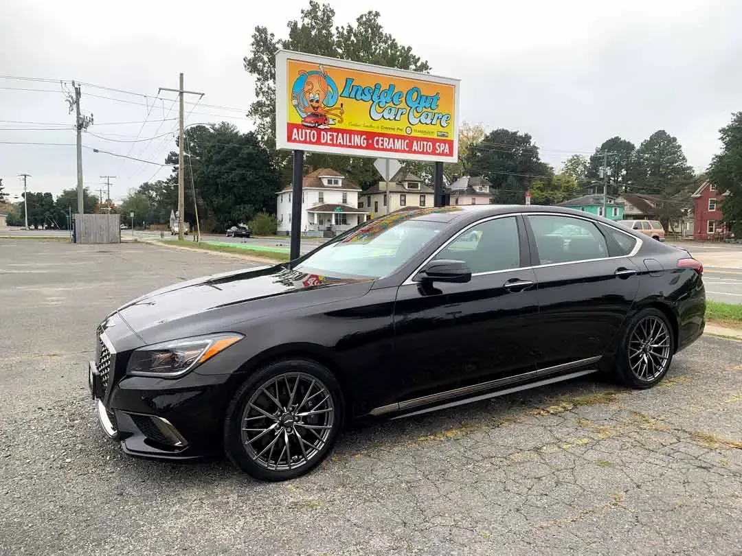 A black car is parked in front of a car wash sign.