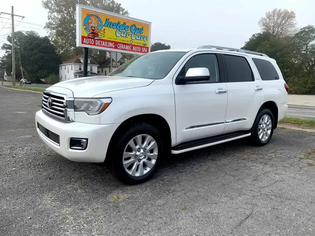 A white toyota sequoia is parked in front of a mexican restaurant.