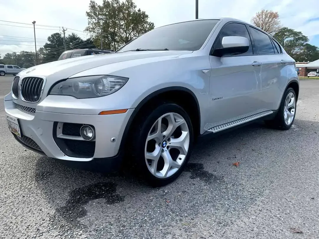 A silver bmw x6 is parked in a parking lot.