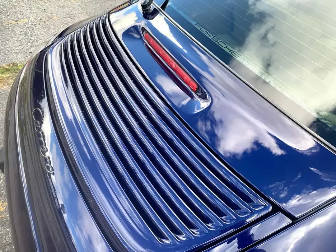 A close up of a blue car with a red tail light