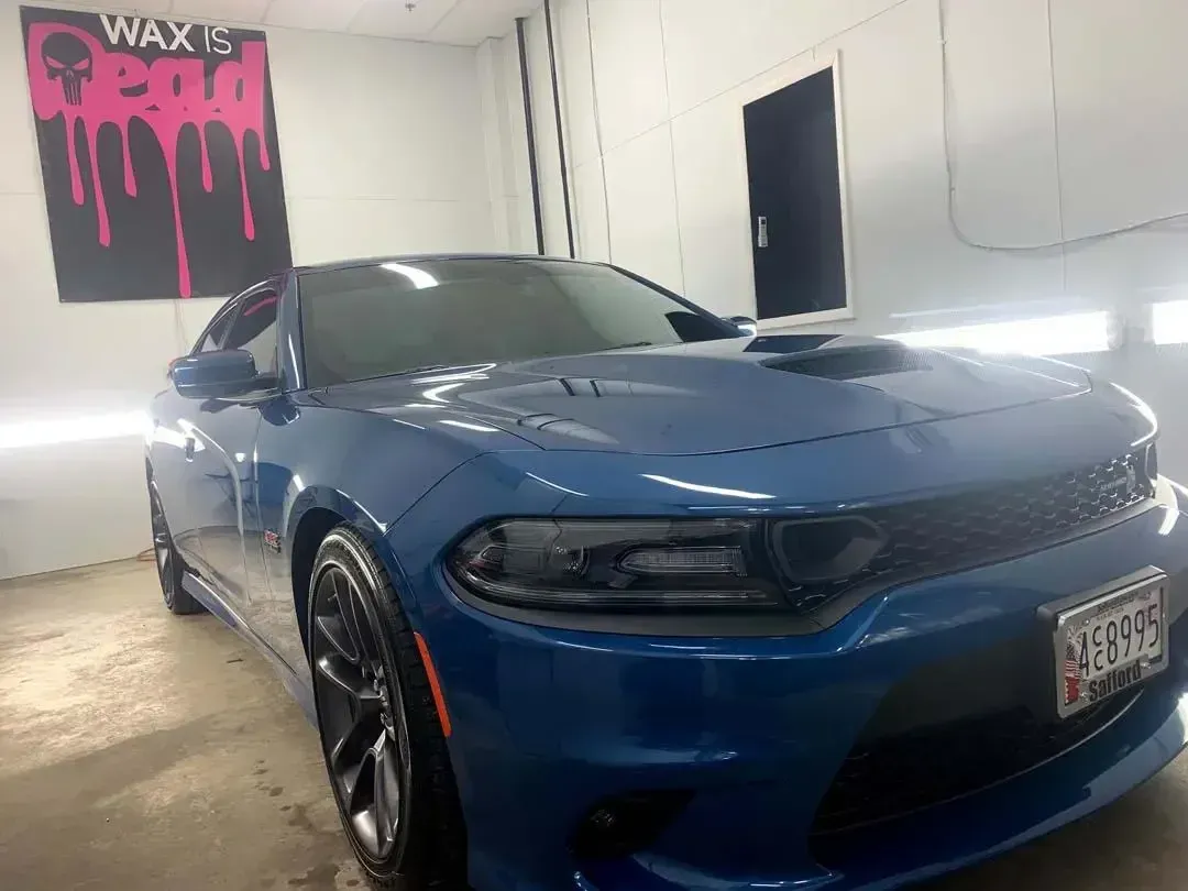 A blue dodge charger is parked in a garage.