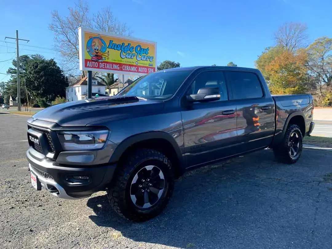 A gray ram truck is parked in a parking lot next to a yellow sign.