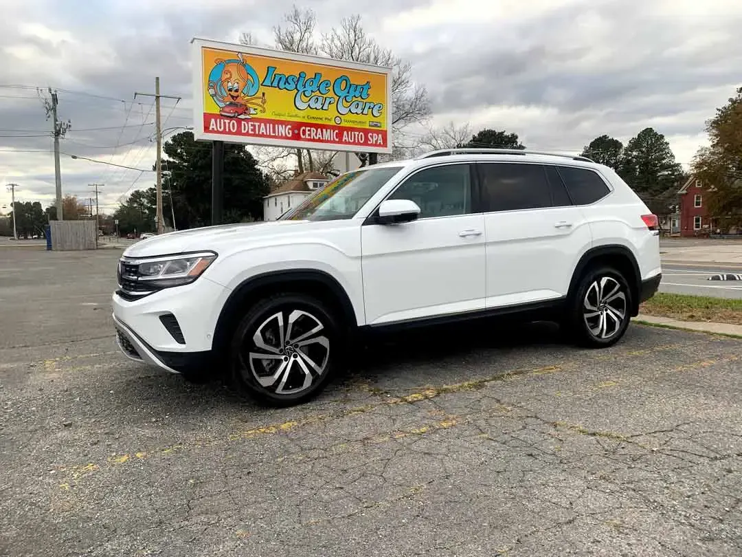 A white suv is parked in a parking lot in front of a sign.