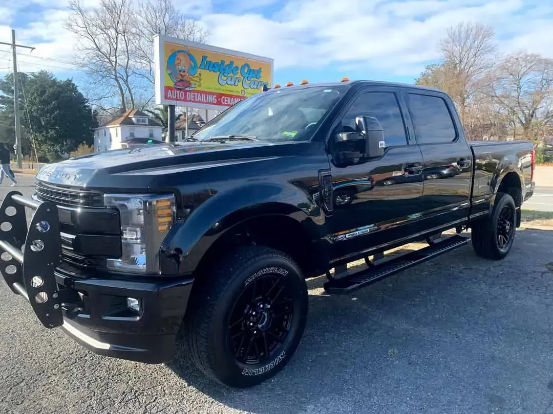 A black pickup truck is parked in front of a car dealership.