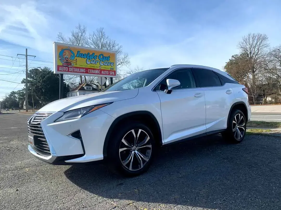 A white lexus rx 350 is parked in front of a billboard.