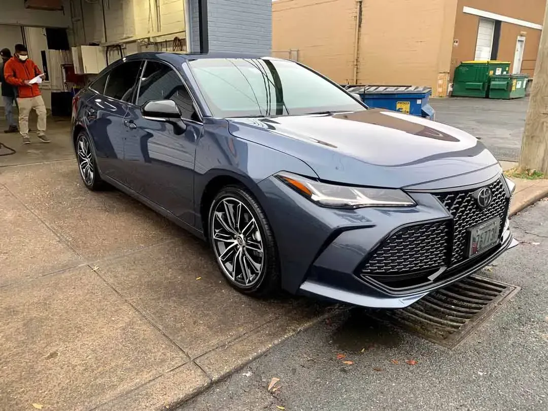 A blue toyota avalon is parked on the side of the road.