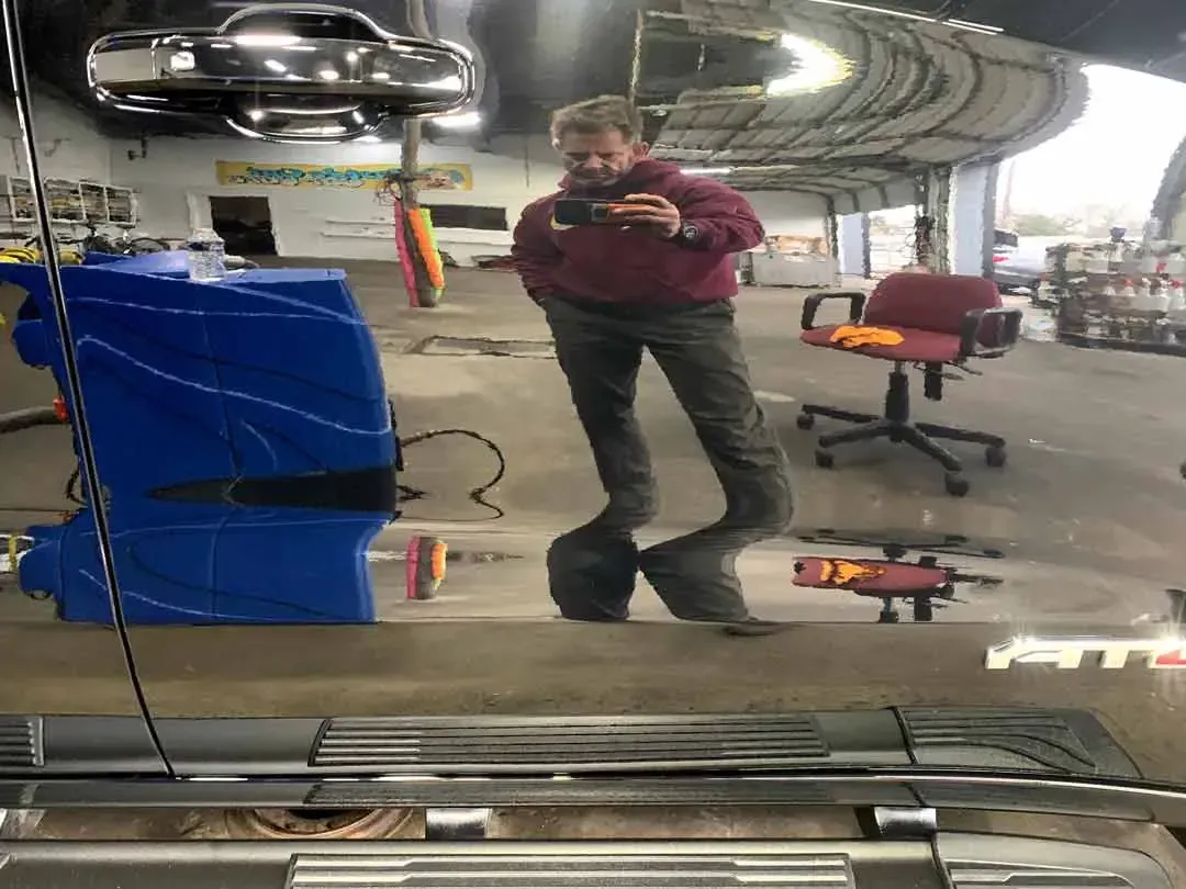 A man is taking a picture of himself in a mirror in a garage.