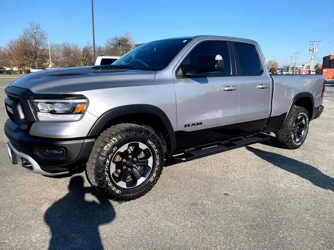 A silver ram 1500 truck is parked in a parking lot.