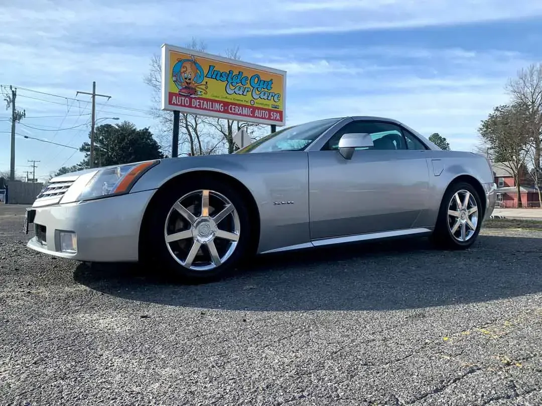 A silver sports car is parked in front of a billboard.