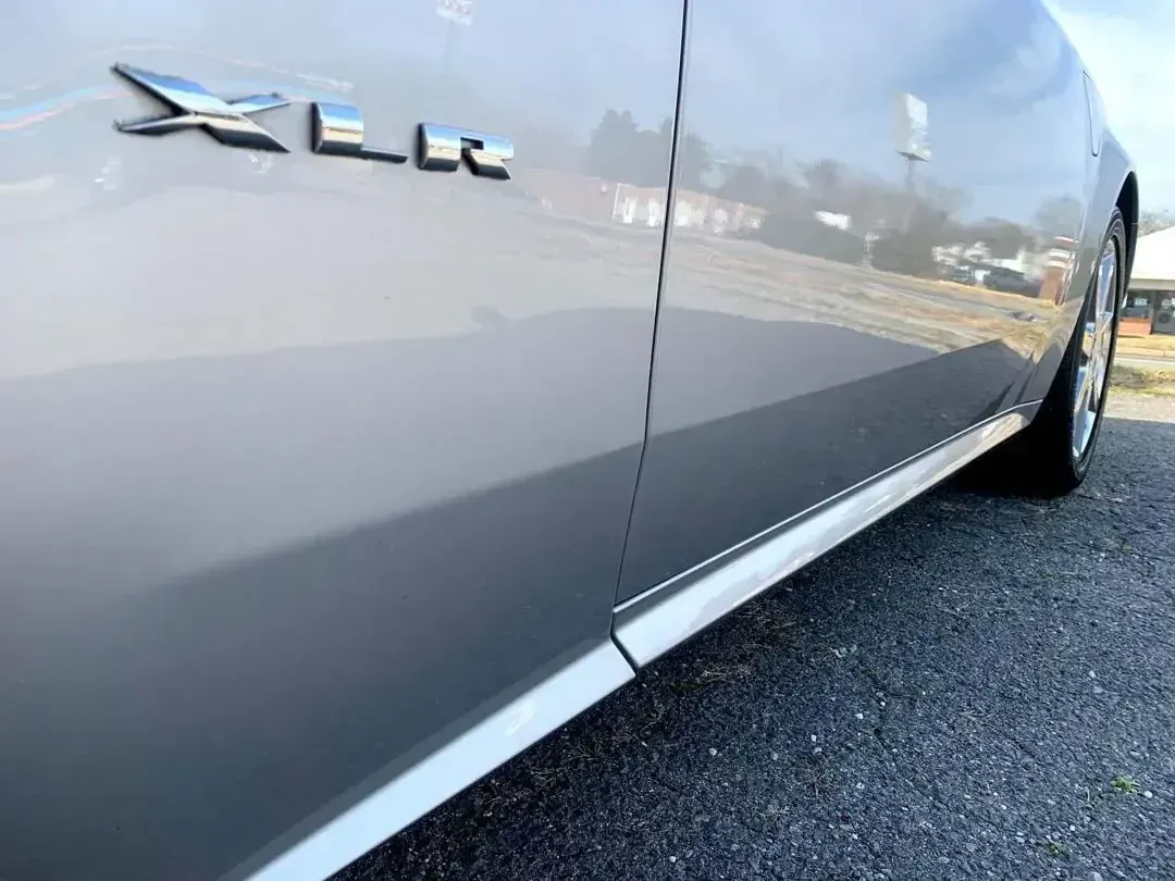 A gray car is parked on the side of the road.