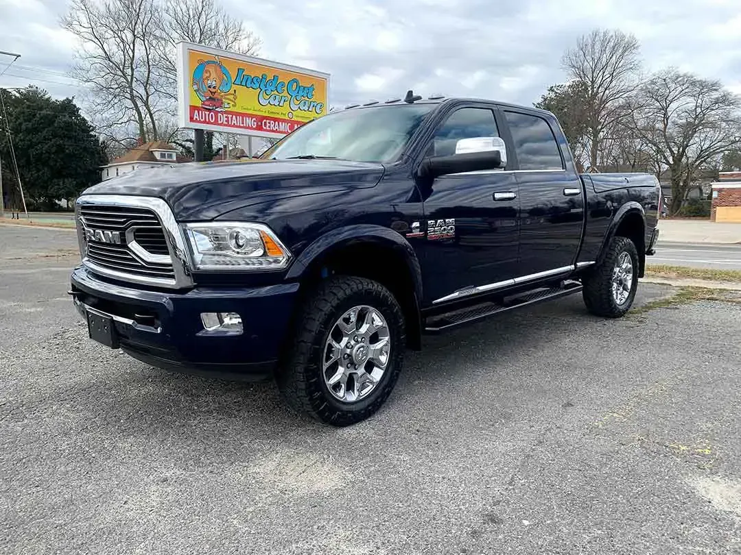 A blue ram truck is parked in a parking lot in front of a building.