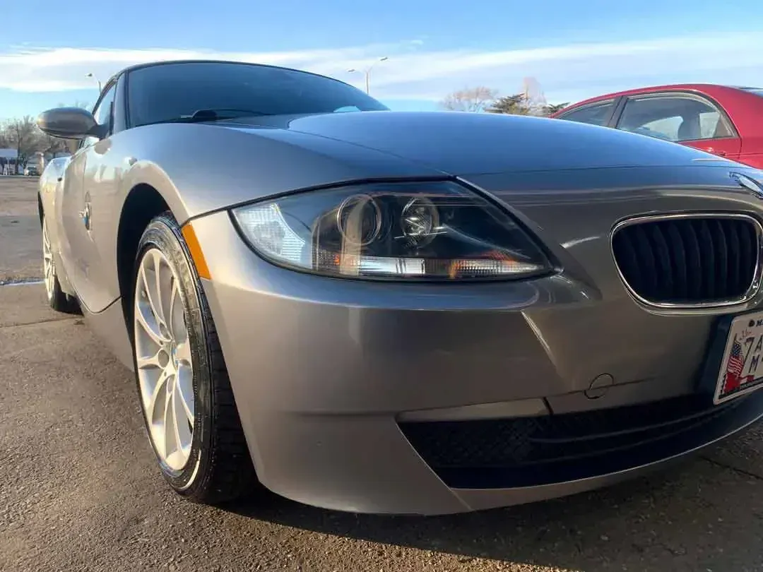 A silver bmw z4 is parked in a parking lot.