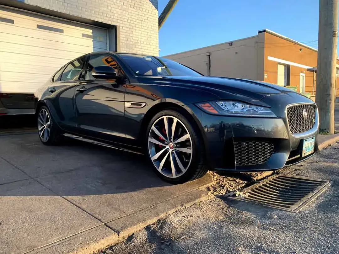 A black jaguar f type is parked on the side of the road.