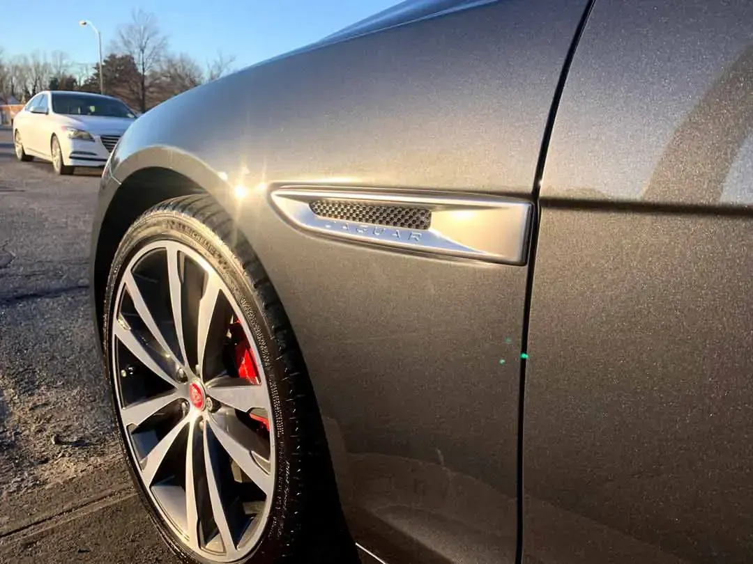 A close up of a car 's fender with a white car in the background.