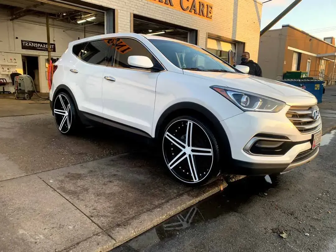 A white hyundai santa fe is parked in front of a garage.
