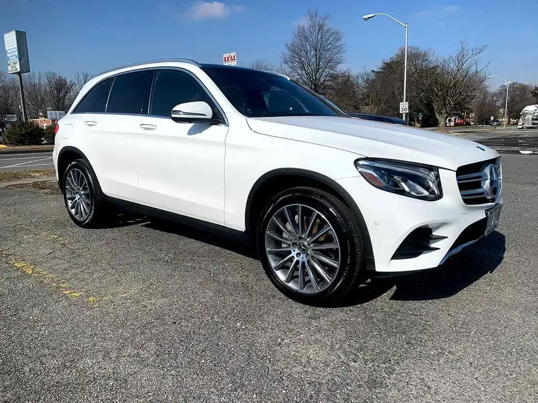 A white mercedes benz glc coupe is parked in a parking lot.
