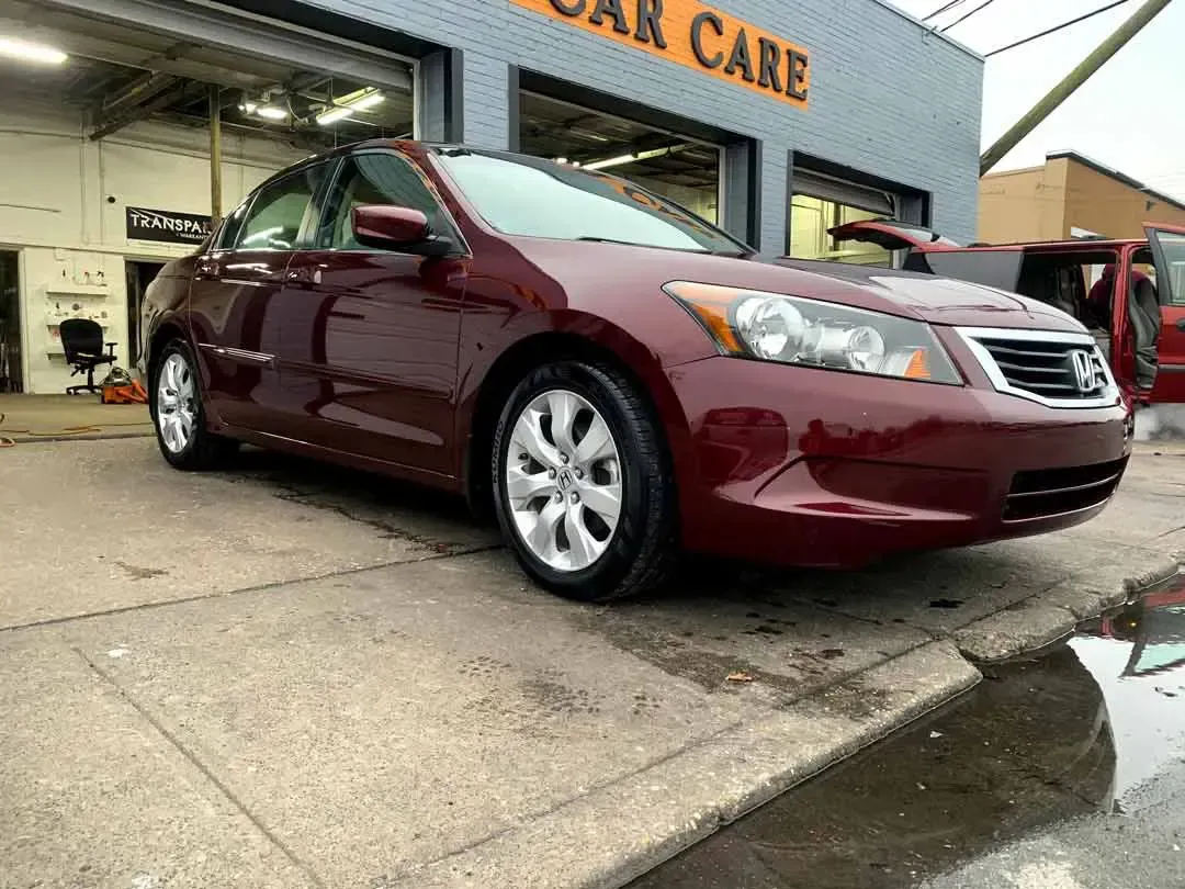A red car is parked in front of a car care shop.