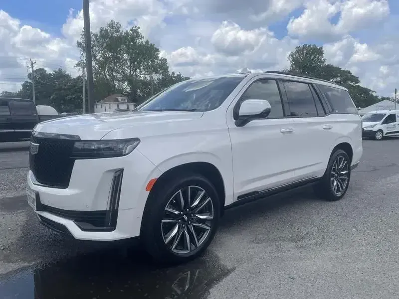 A white cadillac escalade is parked in a parking lot.