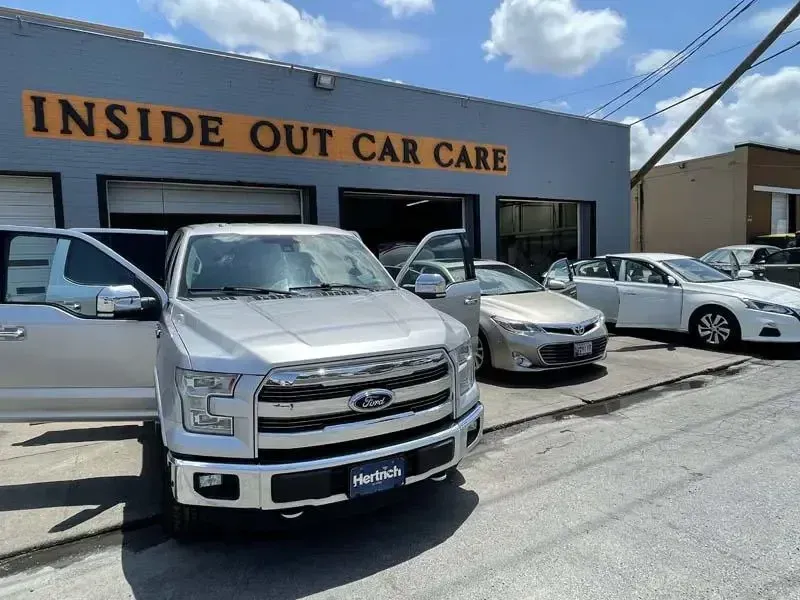 A silver truck is parked in front of a building that says inside out car care.