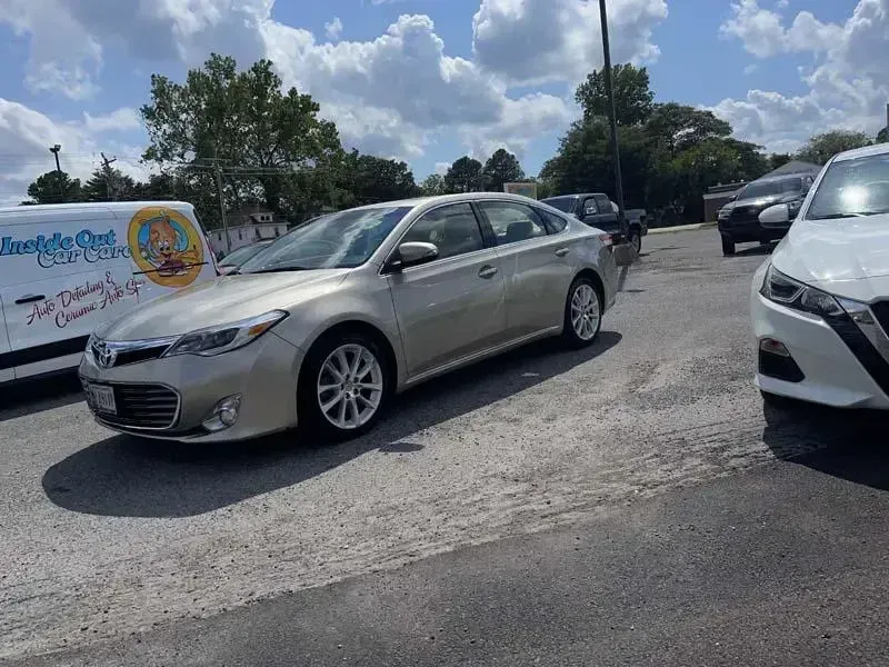 A silver car is parked next to a white van in a parking lot.