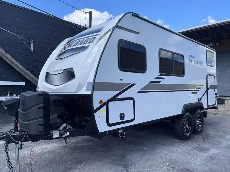 A white trailer is parked in front of a building.