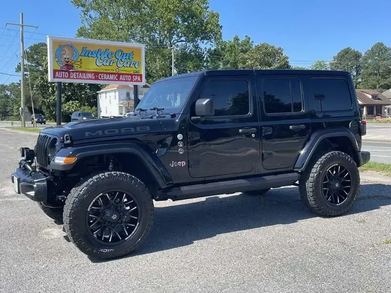 A black jeep wrangler is parked in front of a car wash.