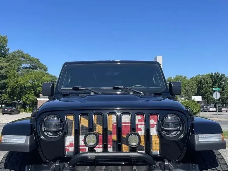 A black jeep with a checkered grille is parked in a parking lot.