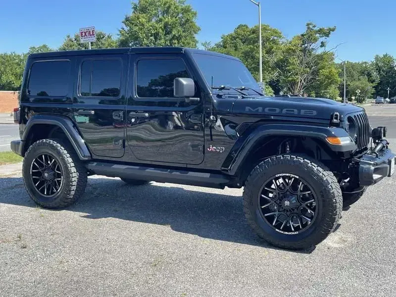 A black jeep wrangler is parked on the side of the road.