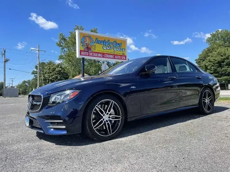 A black mercedes benz e63 amg is parked in front of a sign.