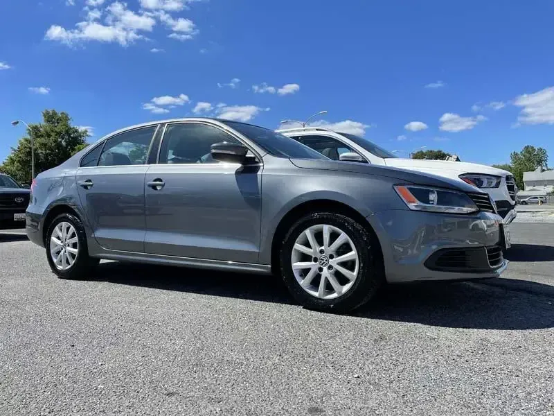 A silver volkswagen jetta is parked in a parking lot.