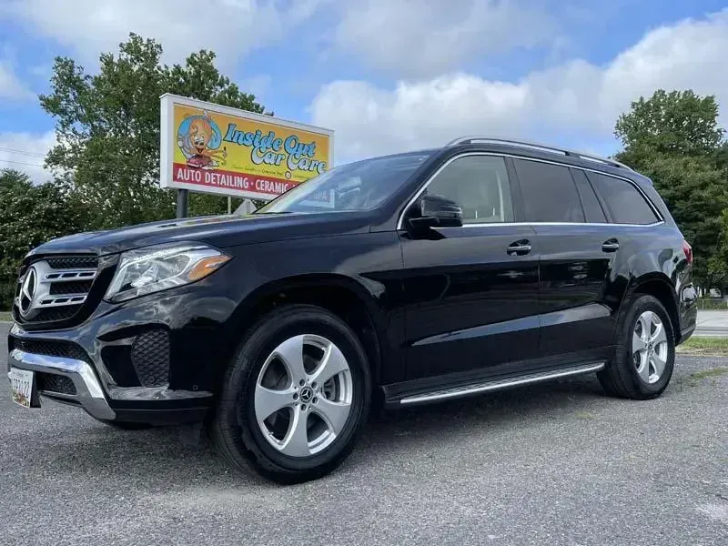 A black mercedes benz gl 550 is parked in front of a sign.